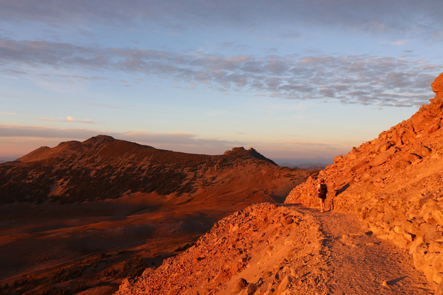 A hiker on a red rock ridge glowing at dusk